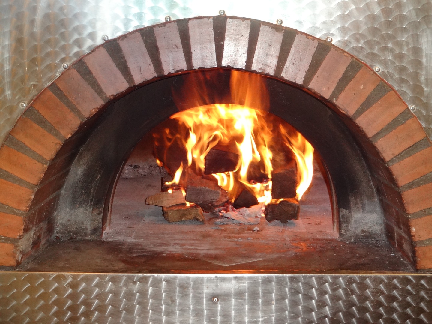 A brick oven with fire burning inside of it.