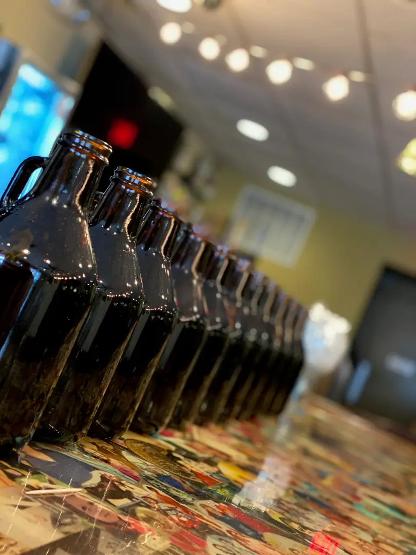 A row of brown beer bottles on top of a table.